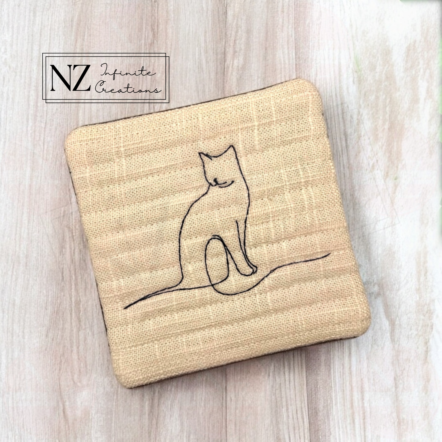 Cat Line Art Mug Rug featuring an embroidered minimalist cat design. Made from linen fabric and batting, this 4.25" by 4.25" mug rug is perfect for cat lovers to protect surfaces while enjoying their favorite drink.